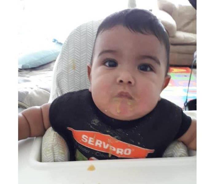 Baby in SERVPRO t-shirt with food on face.