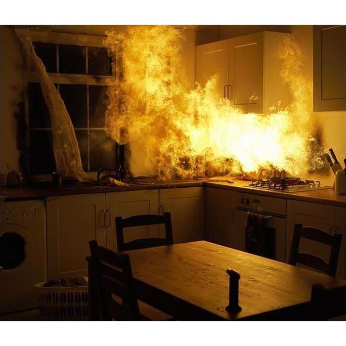 Kitchen on fire with flames shooting out of a kitchen cabinet 