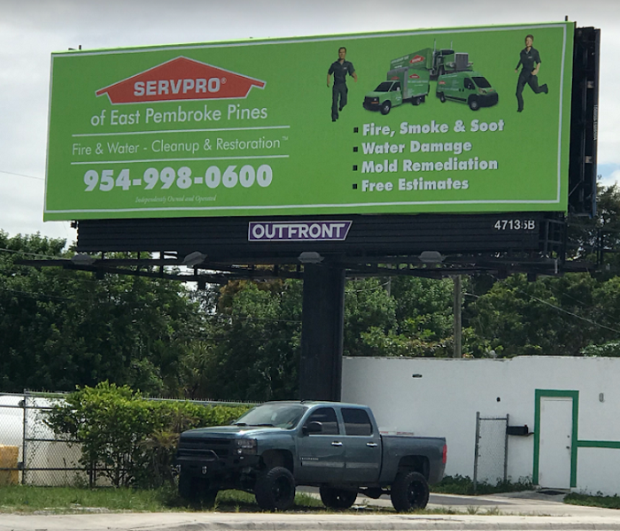 Large billboard advertising SERVPRO.  Truck underneath billboard.