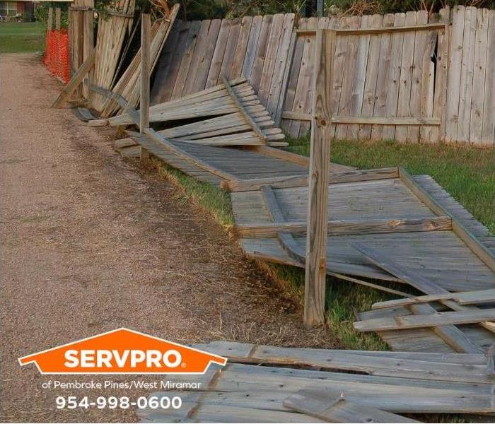 A backyard fence is blown over by a hurricane.